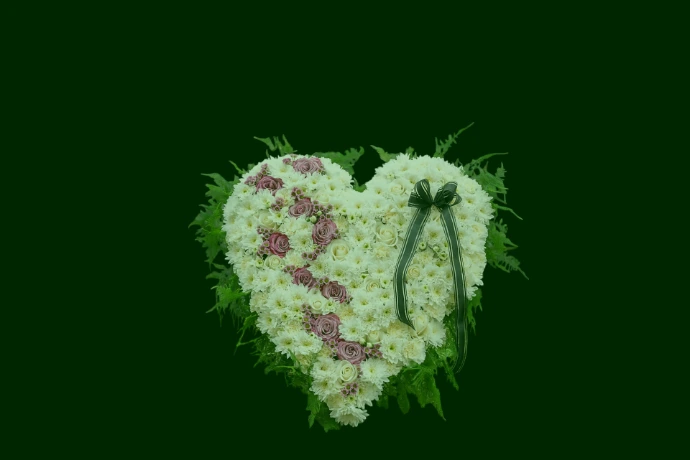 A heart-shaped floral arrangement with white and purple flowers.